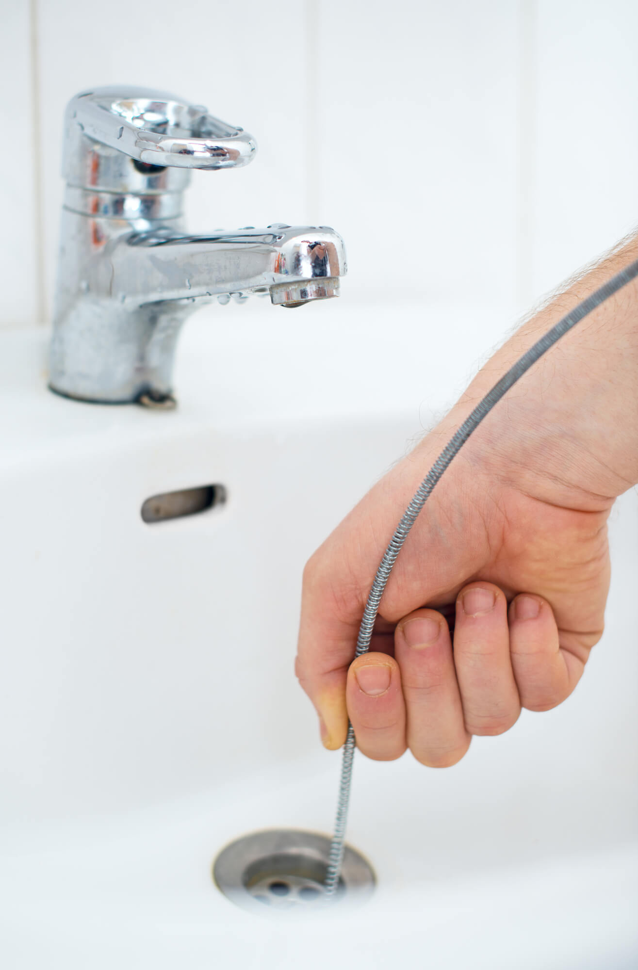 plumber using a snake down bathroom sink