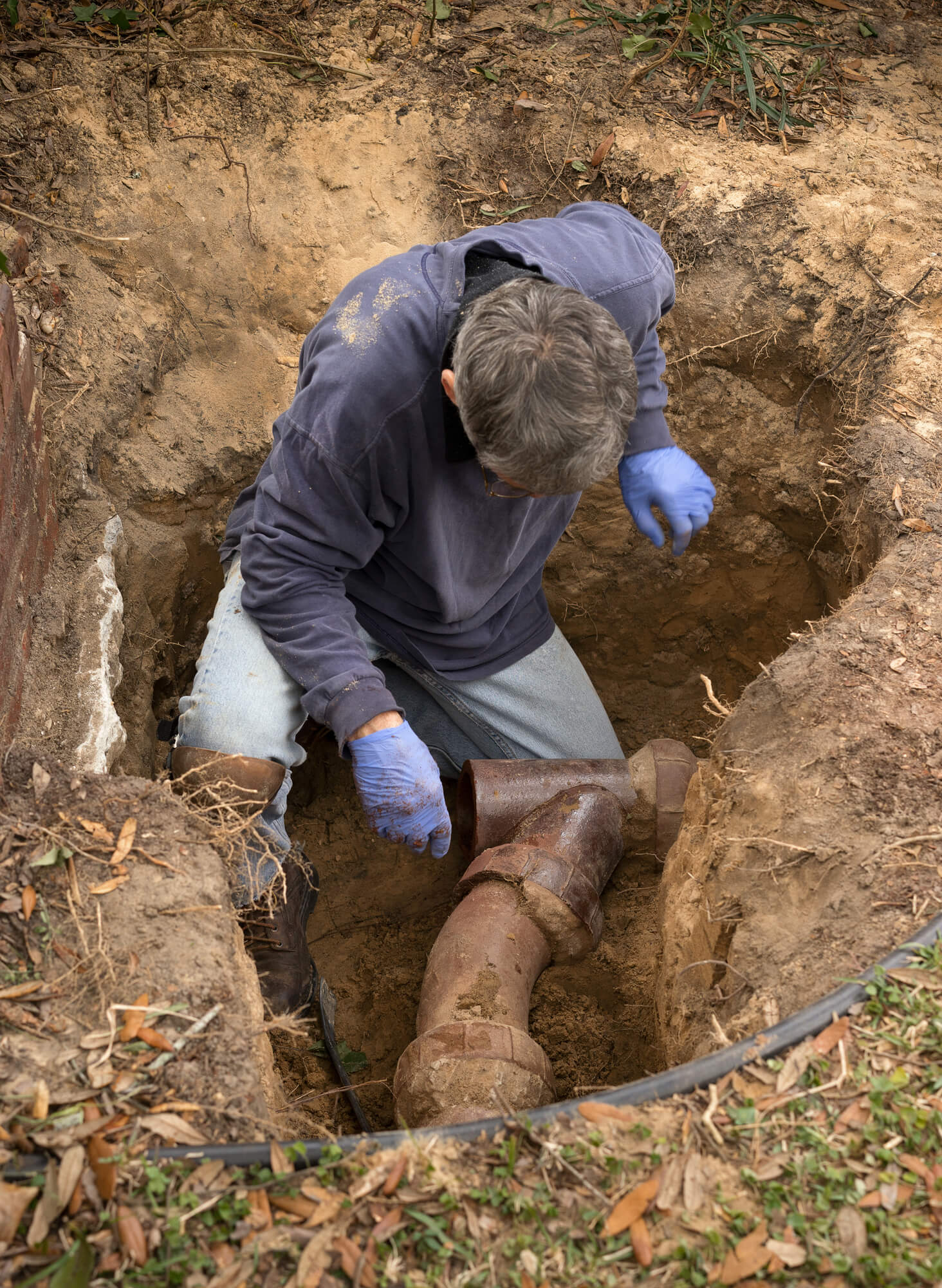 plumber inspecting excavated pipes