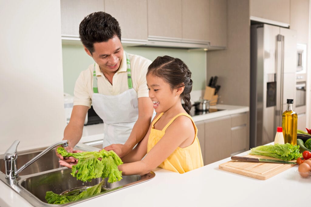 Father and daughter washing lettuce