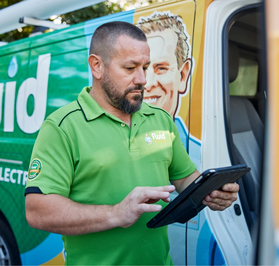 Fluid technician using a tablet beside a branded service van.