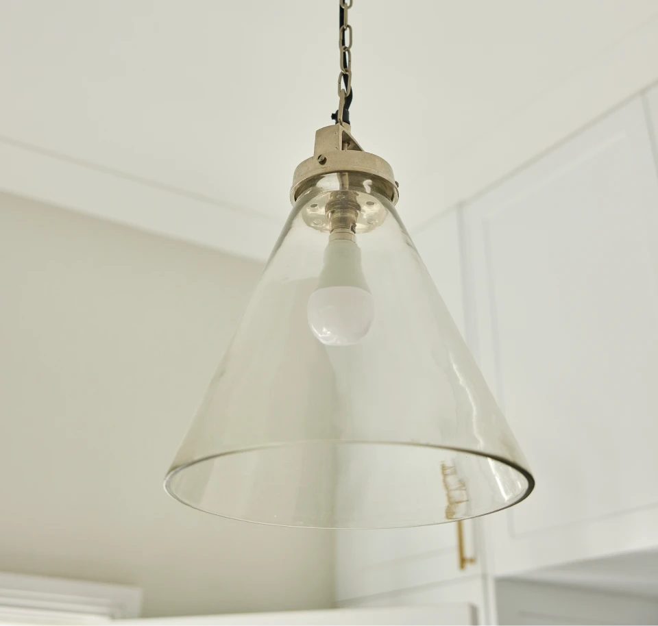 Clear glass pendant light fixture hanging from the ceiling in a bright interior space.